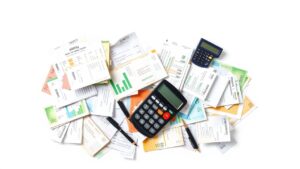 Een rommelig kantoorbureau met rekeningen, calculator en administratieve documenten.